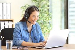 smiling woman with headset sitting at laptop