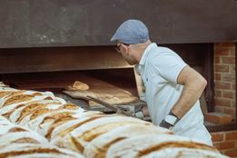 baker baking bread in brick oven